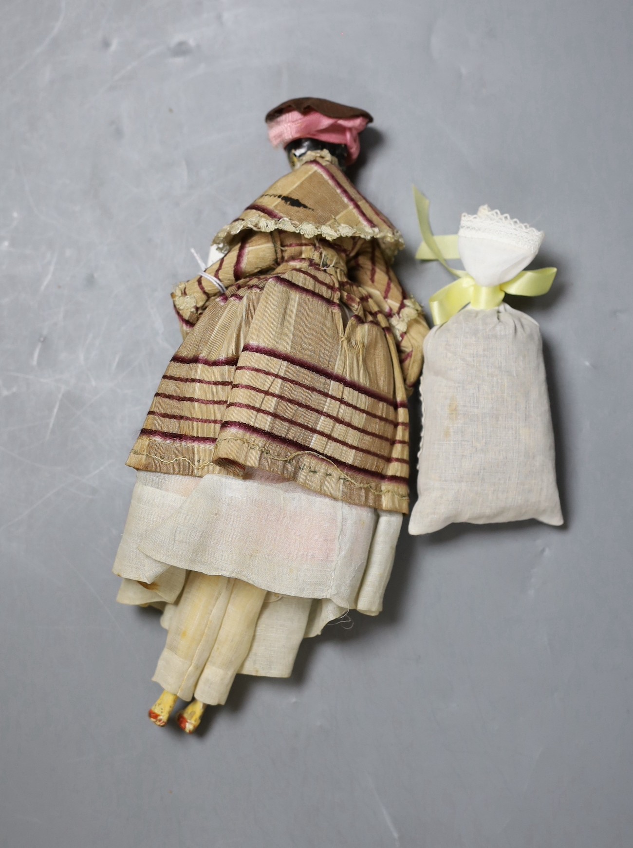 An early 19th century peg doll, wearing contemporary costume, 25.5 cm long